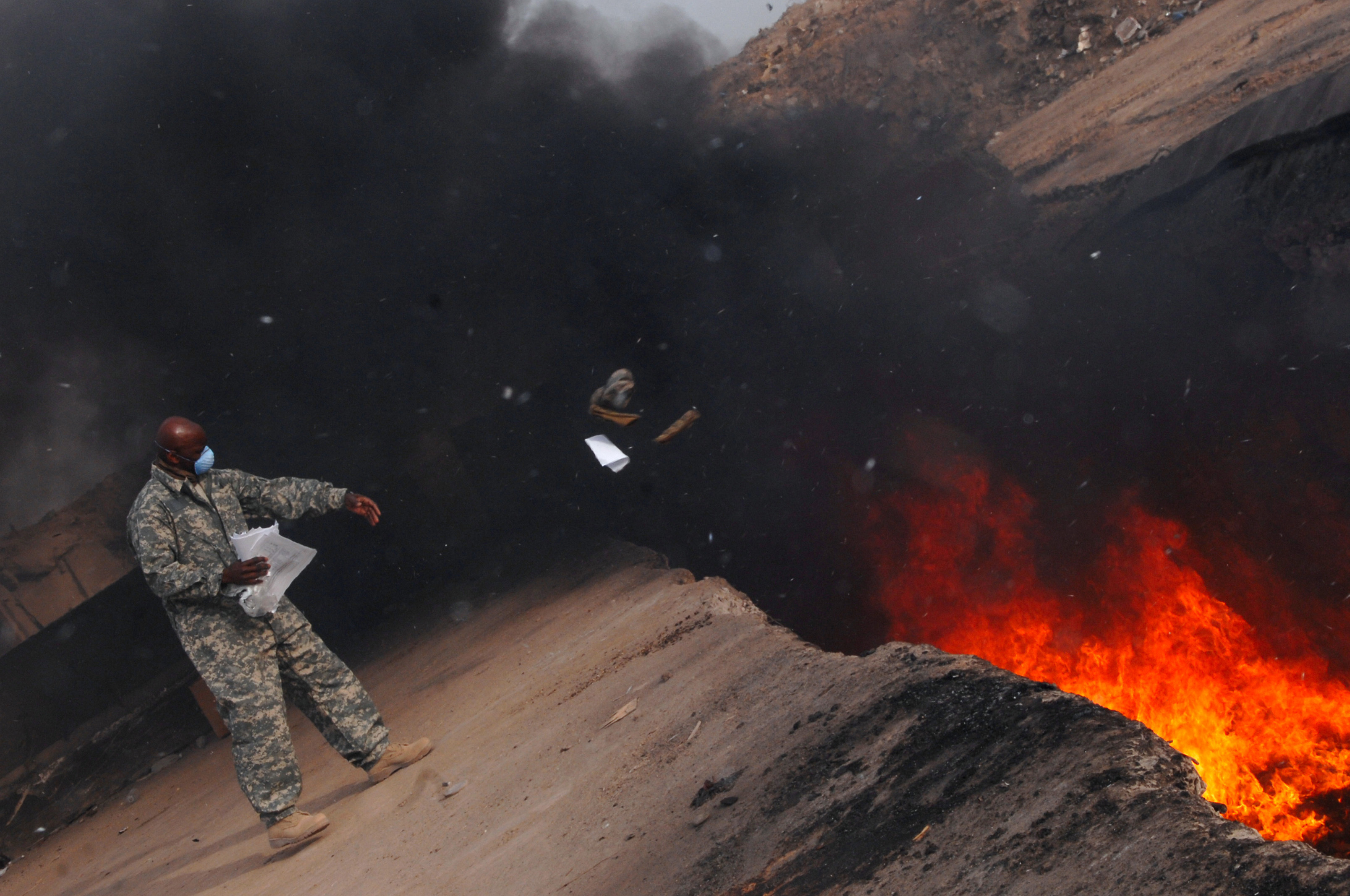 Master Sgt. Darryl Sterling, 332nd Expeditionary Logistics Readiness Squadron equipment manager, tosses unserviceable uniform items into a burn pit, March 10. The 332 ELRS has a central collection point that can be used by service members and Department of Defense civilians; unserviceable uniform items are burned. Sergeant Sterling is deployed from Luke Air Force Base, Ariz.